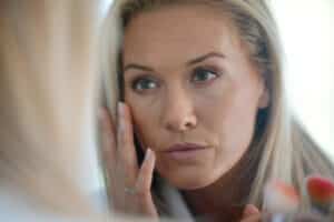 A woman with ectropion looking in the mirror at her eyes